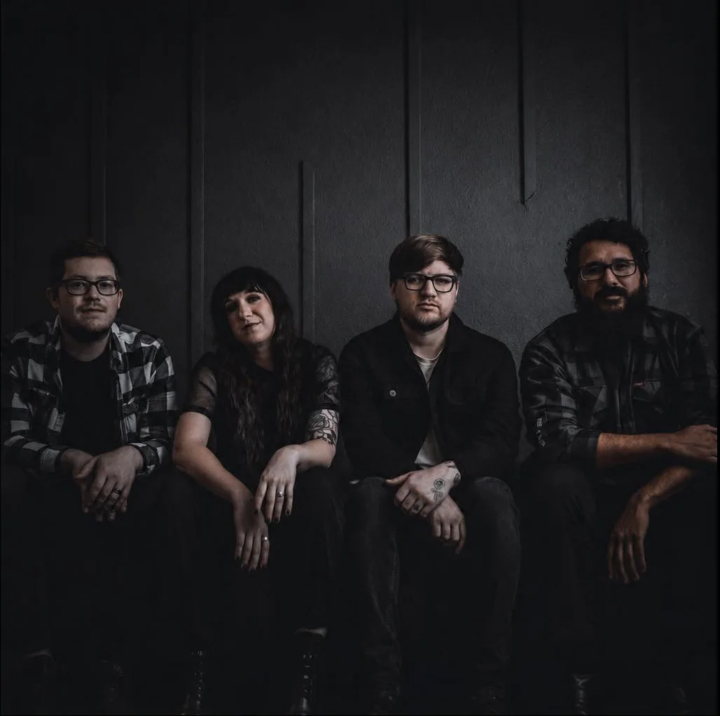 The four members of Divided Me standing together in a wooded setting