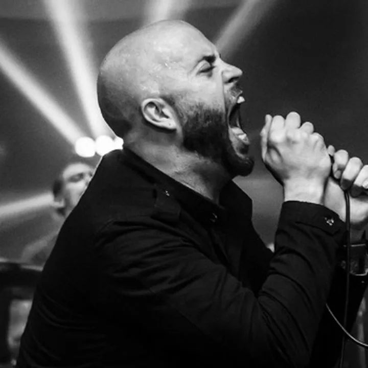 Andrew Schwab of P86:OMNI singing into a microphone onstage